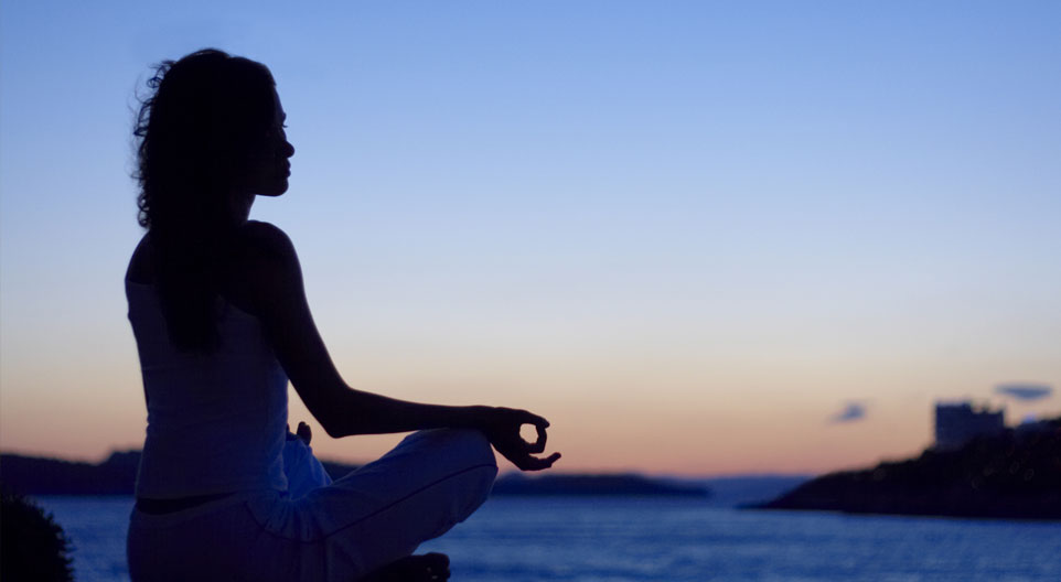 woman seated in yoga pose with wrists resting on knees